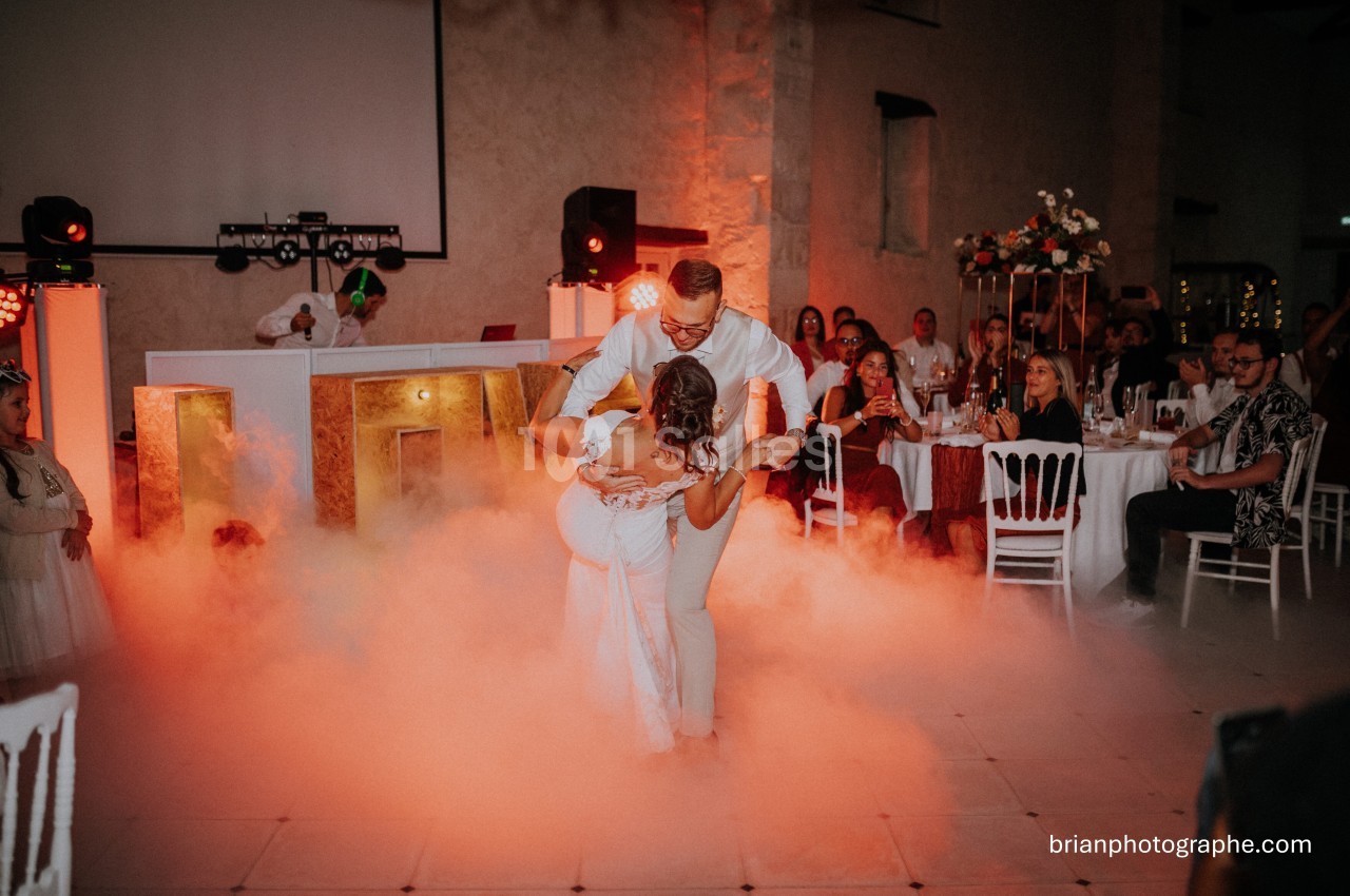 Un couple danse au milieu d'une piste entourée de fumée, sous le regard des invités assis.