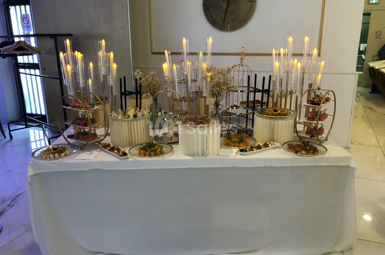 Table garnie de desserts variés et décorée de chandeliers allumés dans un cadre élégant.