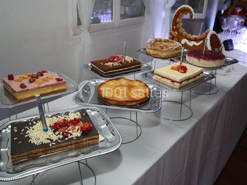 Table dressée avec plusieurs desserts variés, dont des gâteaux, tartes et une pièce montée en arrière-plan.