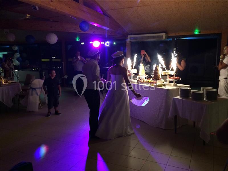 Un couple en tenue de mariage regarde un buffet illuminé de cierges étincelants dans une salle de réception.