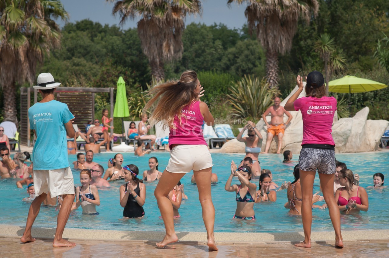 Des animateurs dirigent une activité aquatique avec des participants dans une piscine entourée de végétation tropicale.