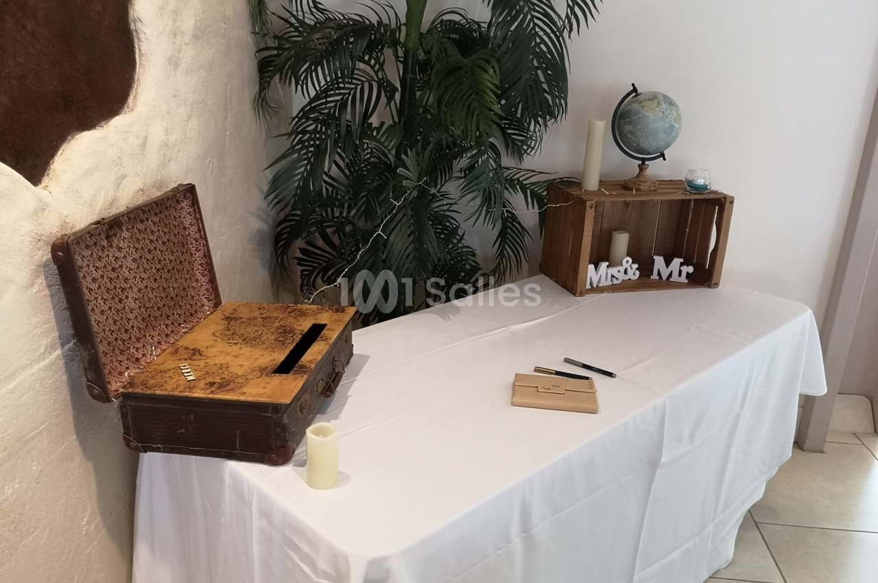 Table décorée avec une valise ancienne, une boîte en bois, un globe terrestre et des éléments de mariage.
