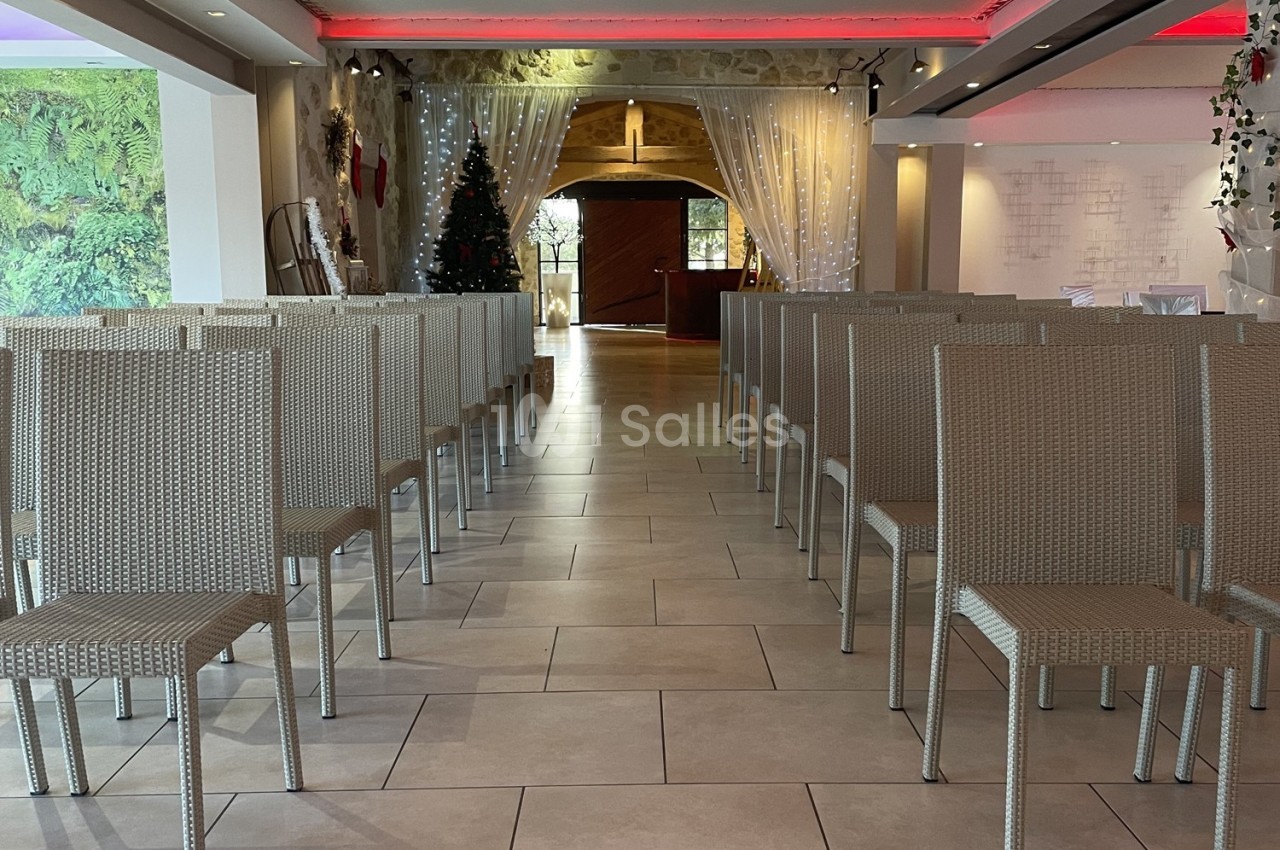 Salle aménagée avec des chaises en rotin alignées, éclairage tamisé et décorations festives en arrière-plan.