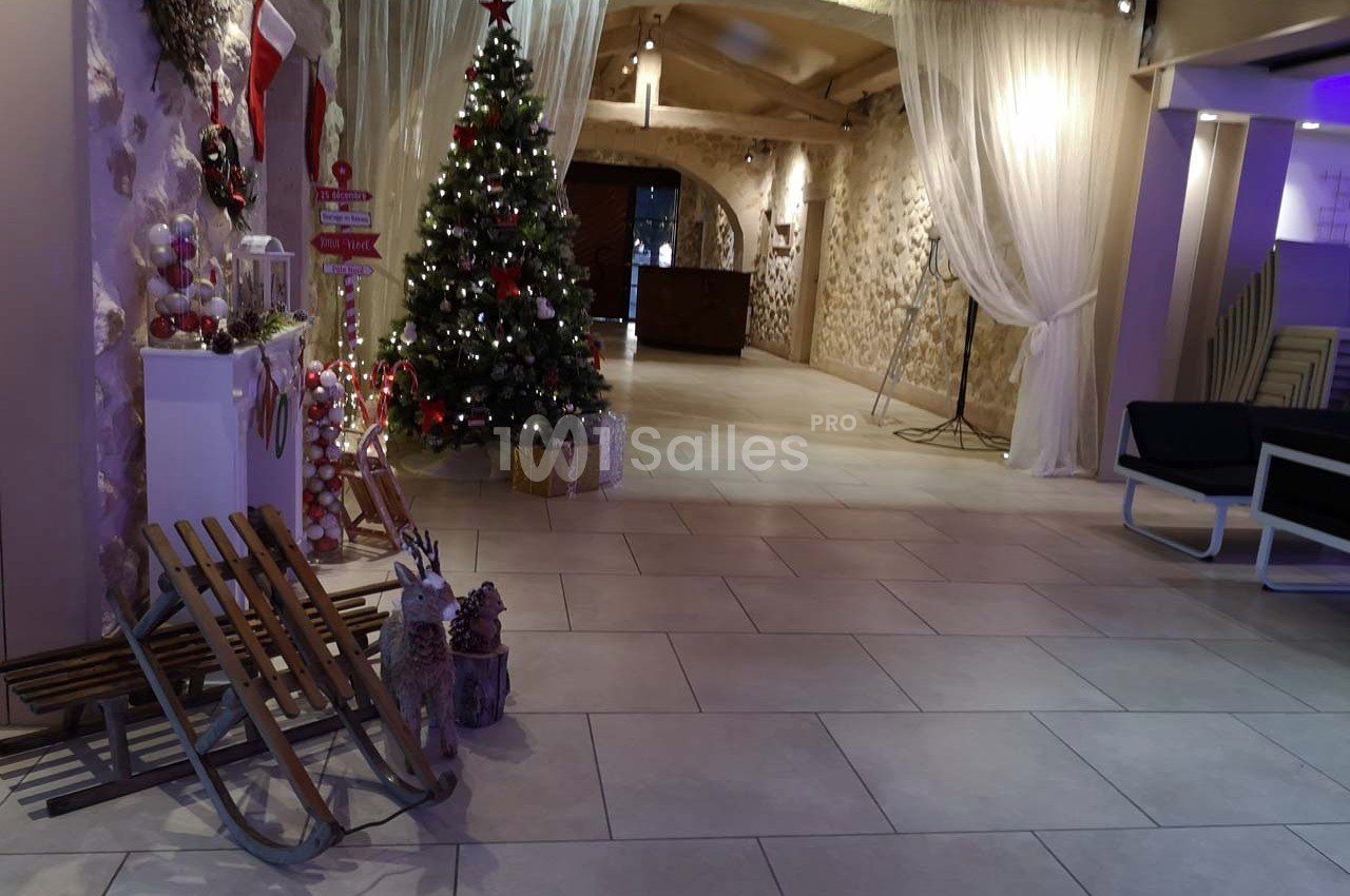 Salle décorée pour Noël avec un sapin illuminé, des cadeaux, des luges en bois et des rideaux blancs.