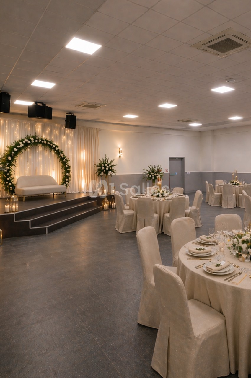 Salle de réception décorée avec des tables rondes dressées, une arche florale lumineuse et un éclairage chaleureux.