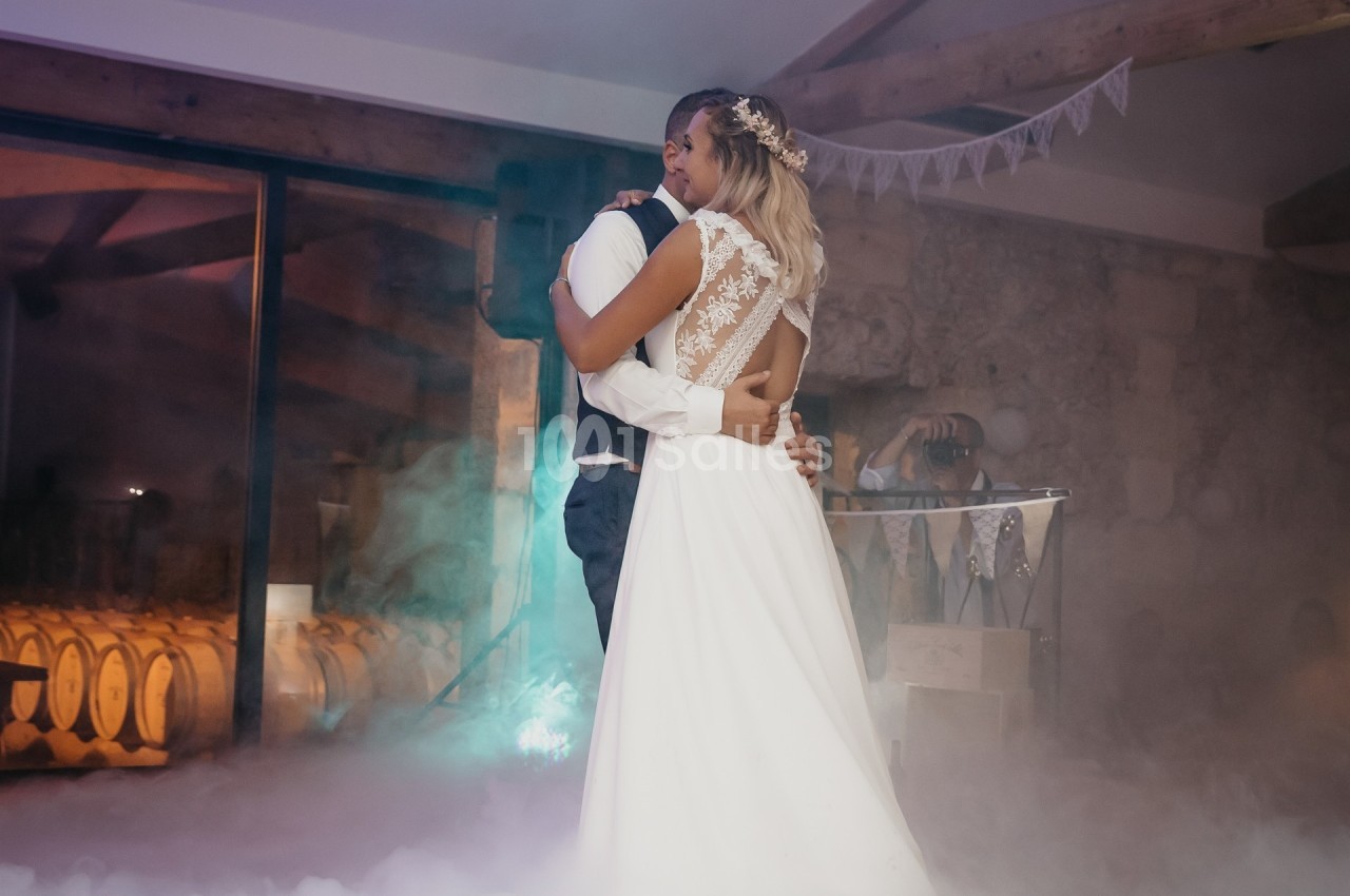Un couple danse dans une salle décorée, entouré de fumée légère et éclairé par des lumières tamisées.