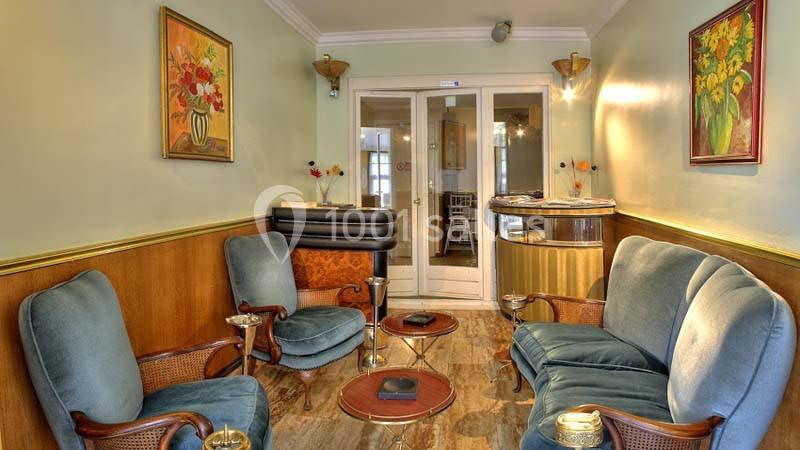 Salle d'attente avec fauteuils bleus, table basse, décorations murales et comptoir d'accueil en arrière-plan.