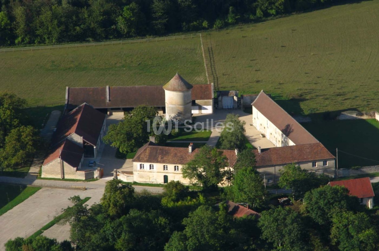Vue aérienne d'un domaine rural avec bâtiments en pierre, toits en tuiles et espaces verts environnants.