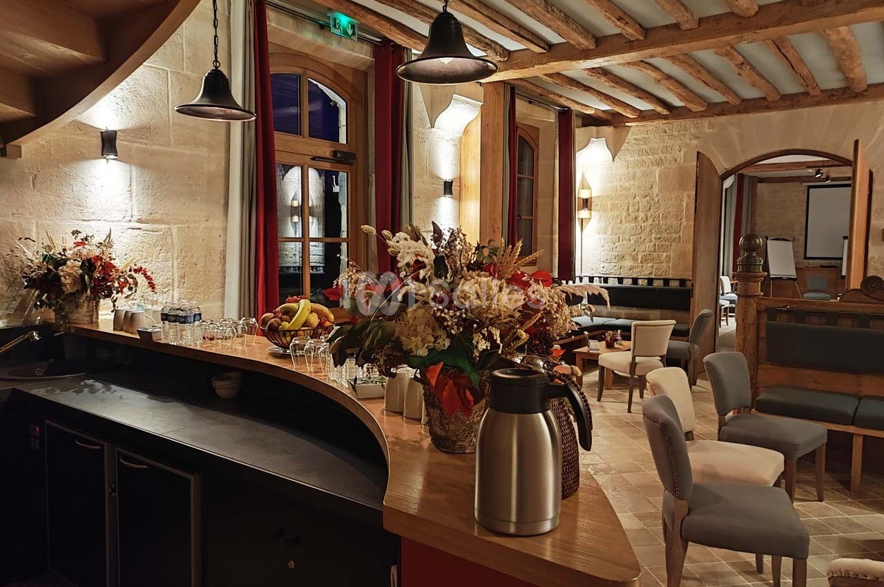 Salle chaleureuse avec un bar en bois, des fleurs décoratives, des tables et des chaises dans un cadre rustique.