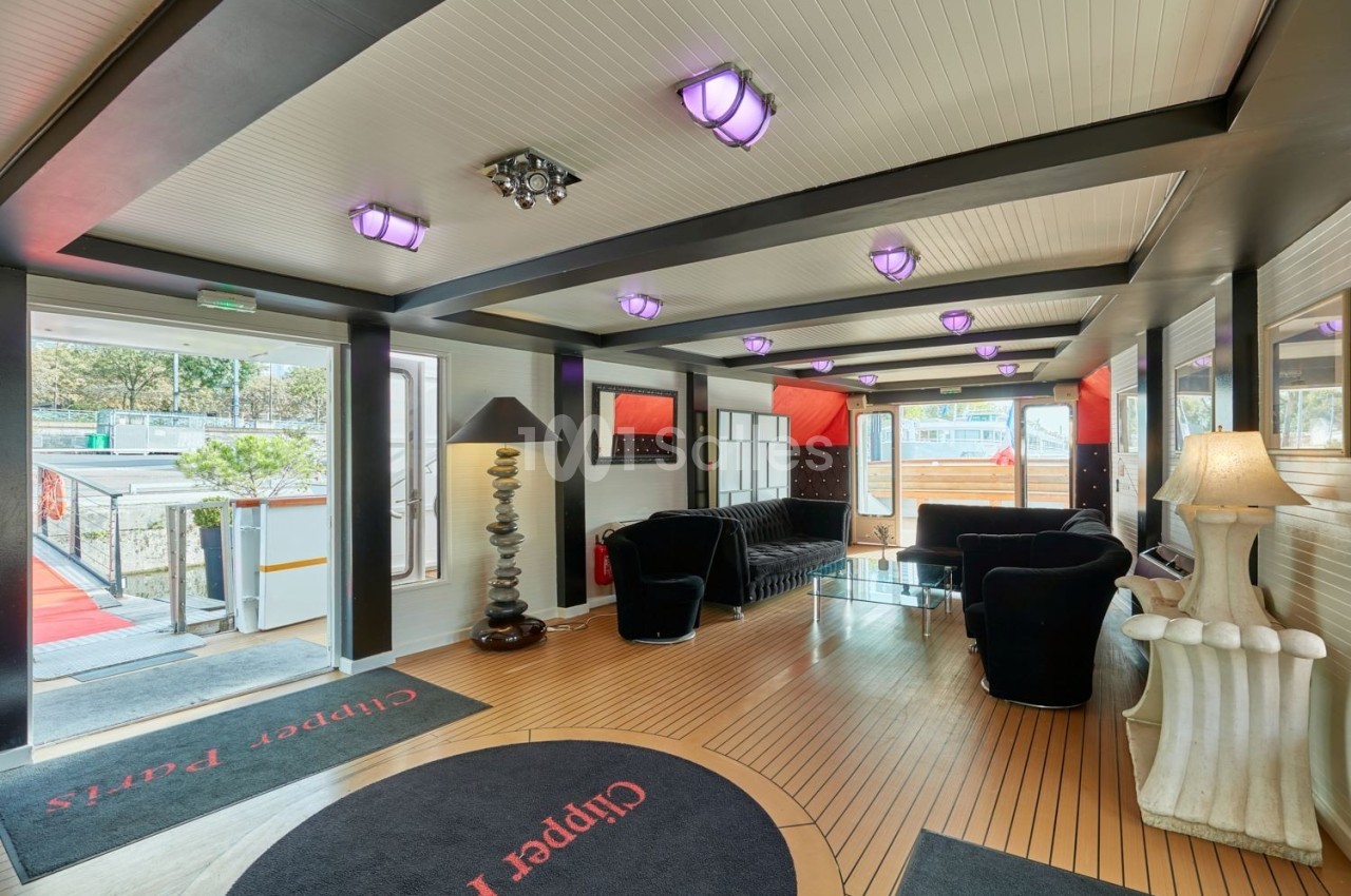 Intérieur lumineux d'un salon avec mobilier moderne, lampes violettes au plafond et vue sur l'extérieur par des baies…