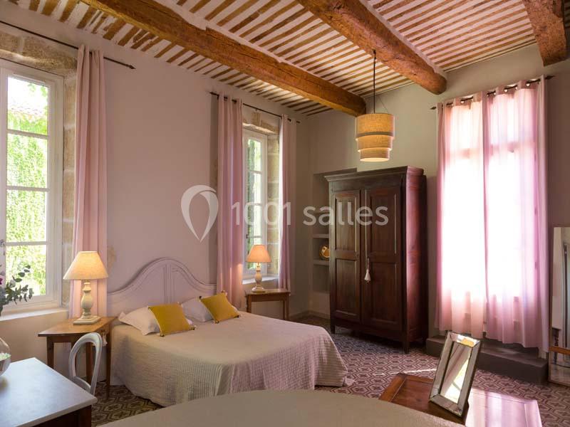 Chambre lumineuse avec lit double, armoire en bois, lampes de chevet et poutres apparentes au plafond.