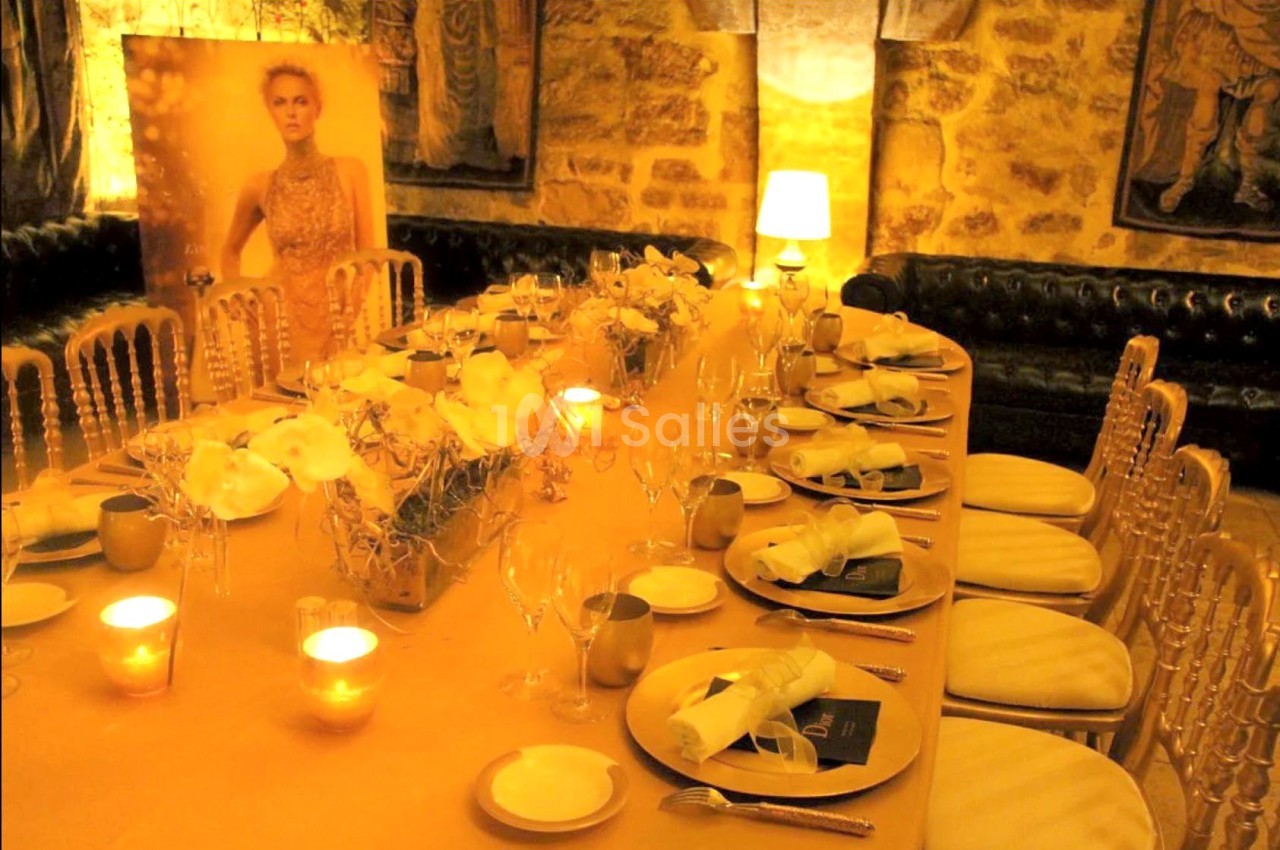 Table élégamment dressée avec des bougies, des fleurs blanches et des chaises dorées dans une ambiance chaleureuse.