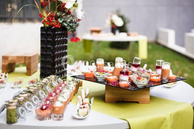 Buffet extérieur avec verrines colorées et décorations florales sur des tables dressées.