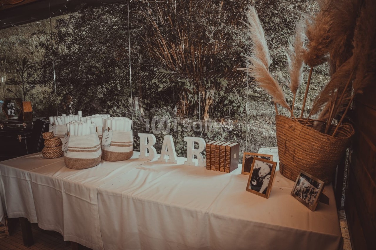 Table décorée avec des paniers, des serviettes, des lettres formant ’BAR’, des cadres photo et des herbes séchées.