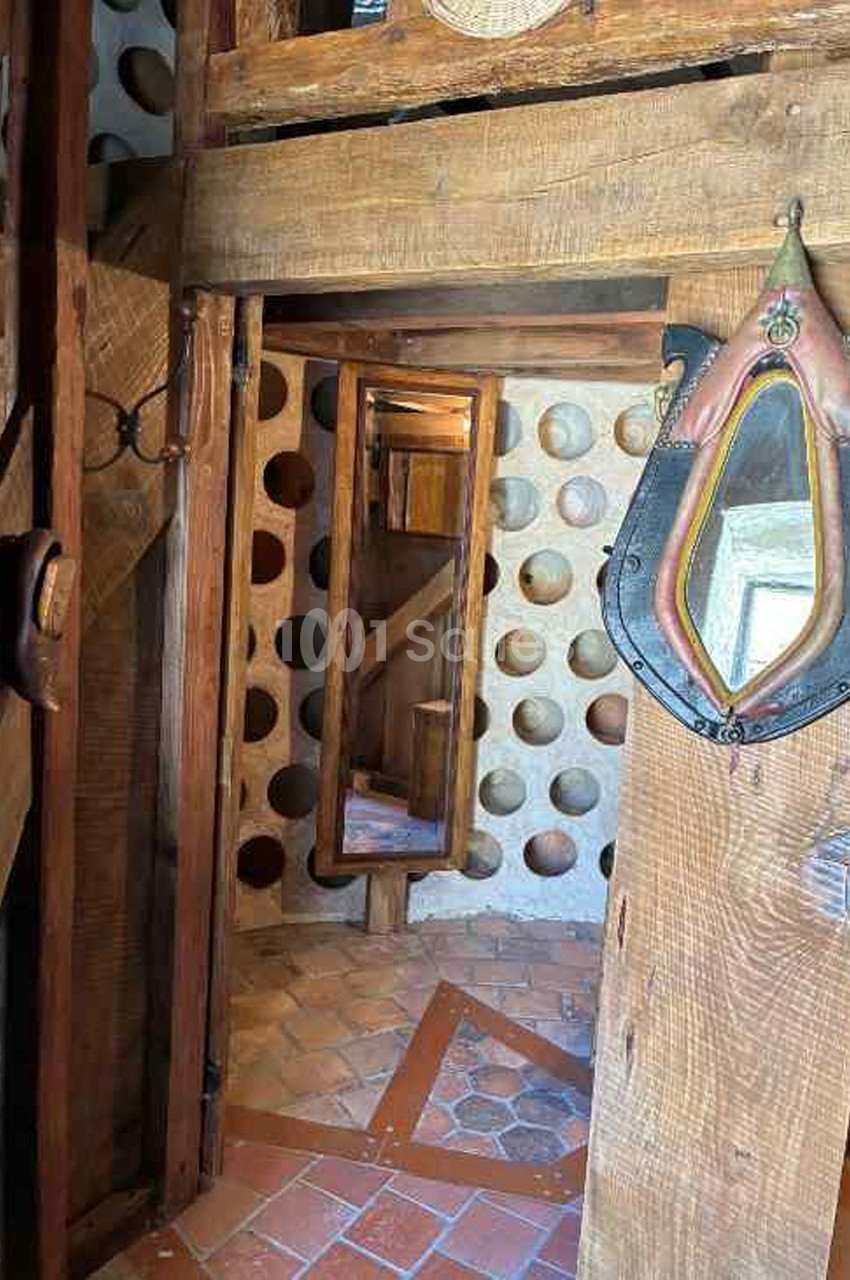 Intérieur en bois avec un miroir, des murs ornés de niches circulaires et un sol en carreaux de terre cuite.