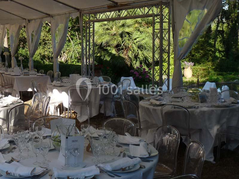 Tables élégamment dressées sous une tente blanche, entourées de végétation luxuriante en arrière-plan.