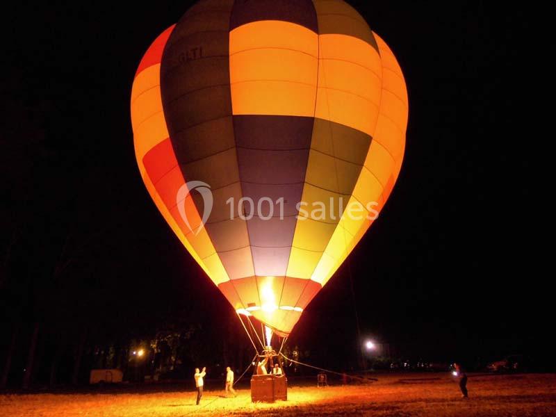 Montgolfière colorée illuminée au sol dans l'obscurité, avec des personnes à proximité pour la préparer.