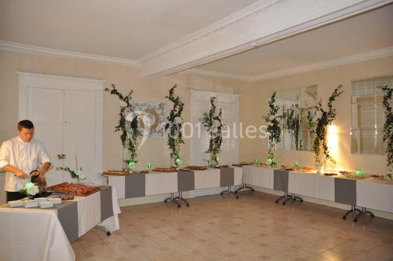 Un buffet décoré avec des plantes et des lumières vertes, un chef prépare des plats sur une table à gauche.