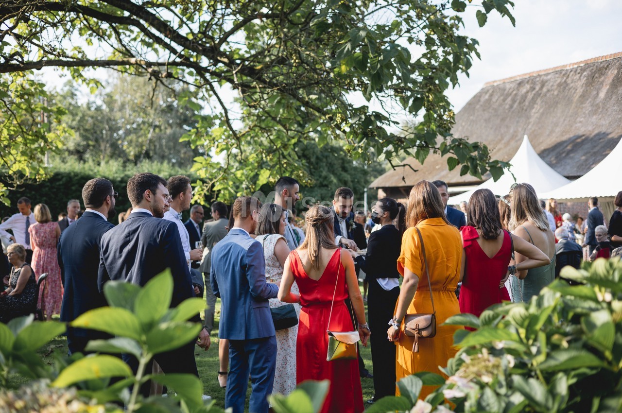 Groupe de personnes debout dans un jardin lors d'un événement en plein air, sous un ciel dégagé.