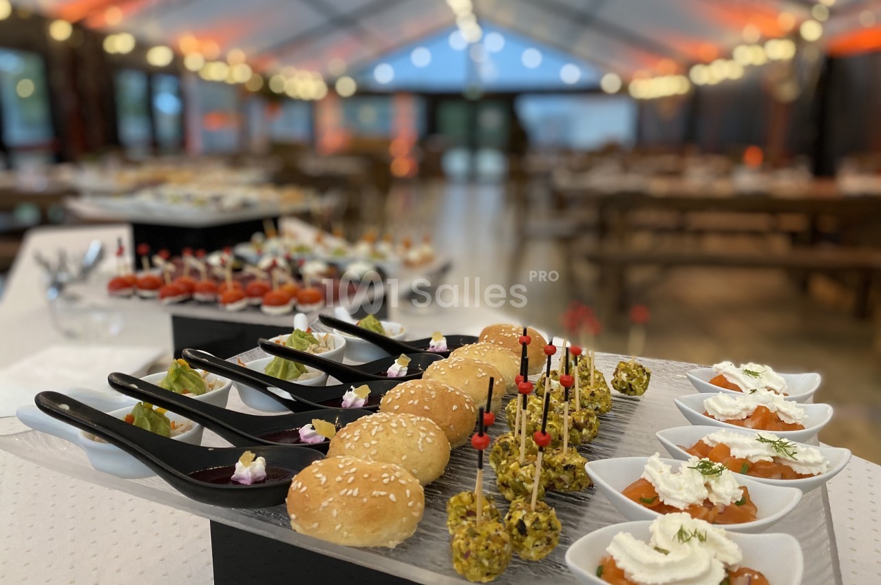 Plateau de bouchées apéritives variées disposées sur une table dans une salle de réception décorée.