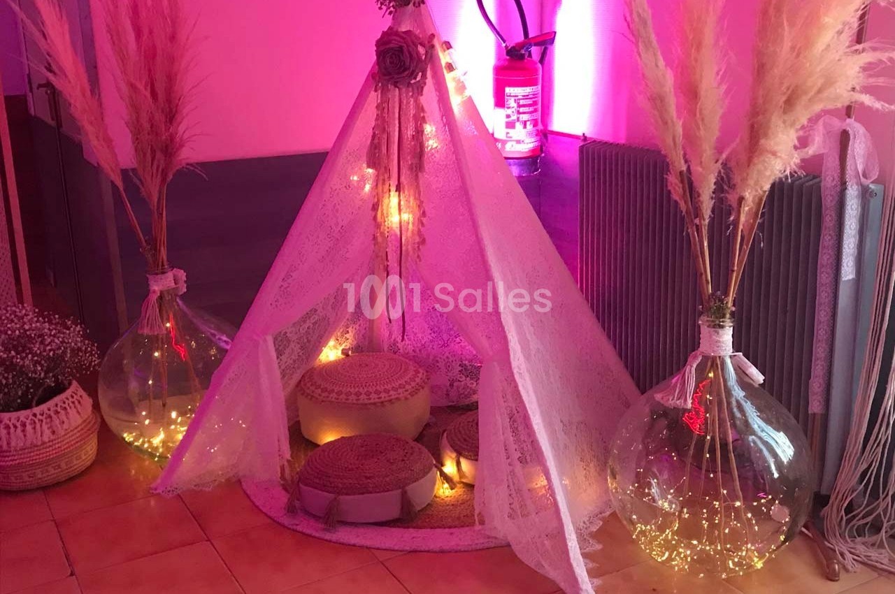 Tente décorative en dentelle avec coussins, entourée de pampas et de guirlandes lumineuses dans un intérieur chaleureux.