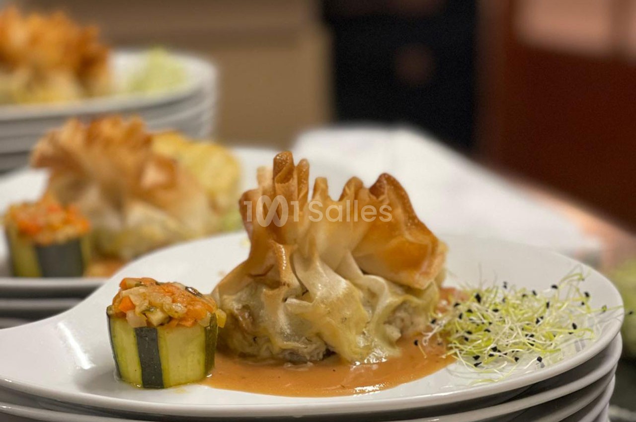 Assiette gastronomique avec une aumônière dorée, une courgette farcie et une sauce, accompagnées de jeunes pousses.