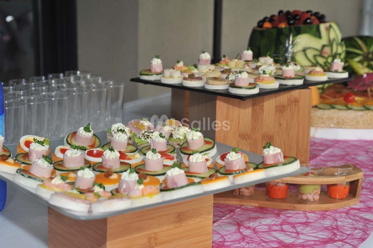 Plateaux de canapés variés avec légumes, fromage et charcuterie, disposés sur une table décorée.