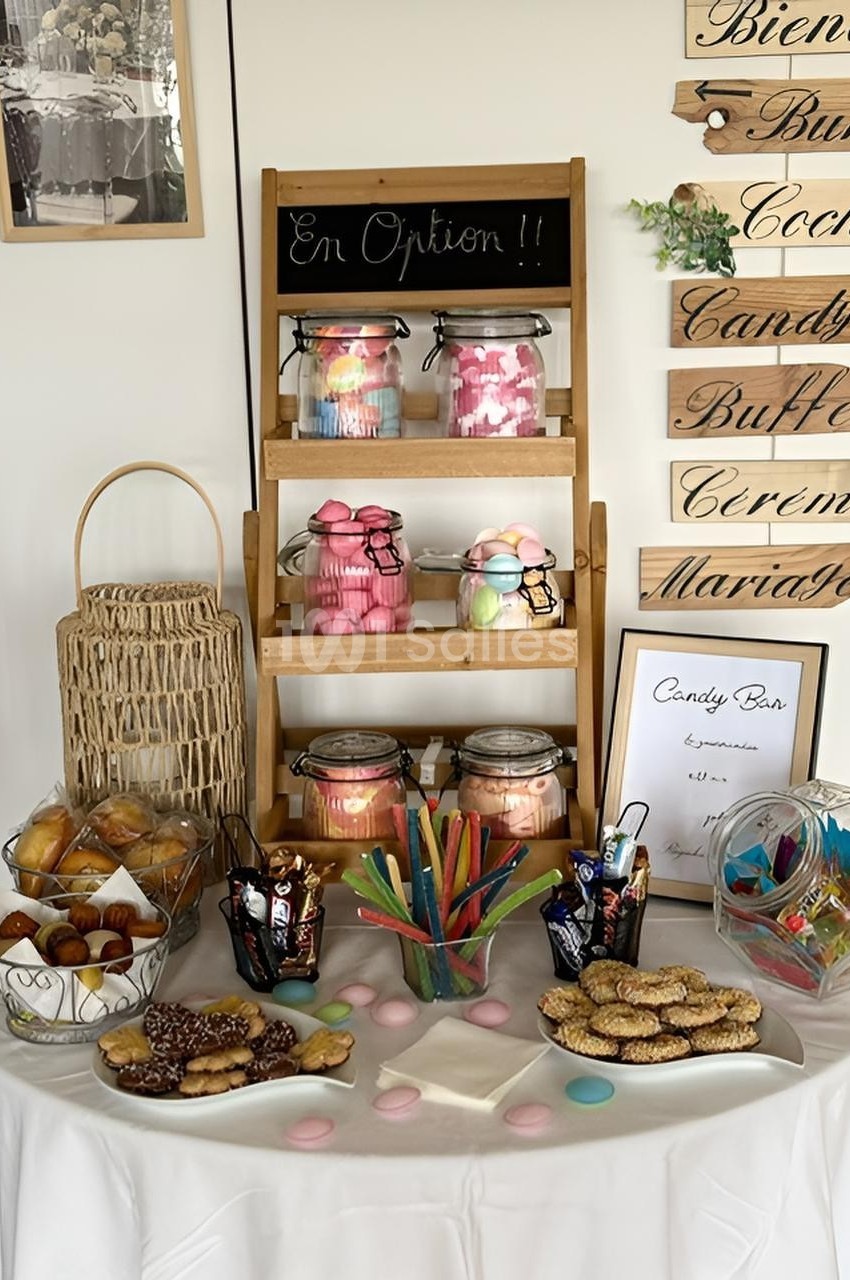Table garnie de bonbons, biscuits et pâtisseries, avec des bocaux et un panneau ’En Option !!’ sur une étagère.