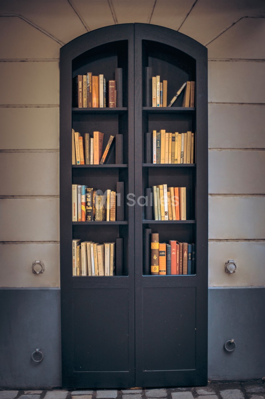 Bibliothèque intégrée dans une façade, remplie de livres aux couvertures variées, dans un cadre urbain.