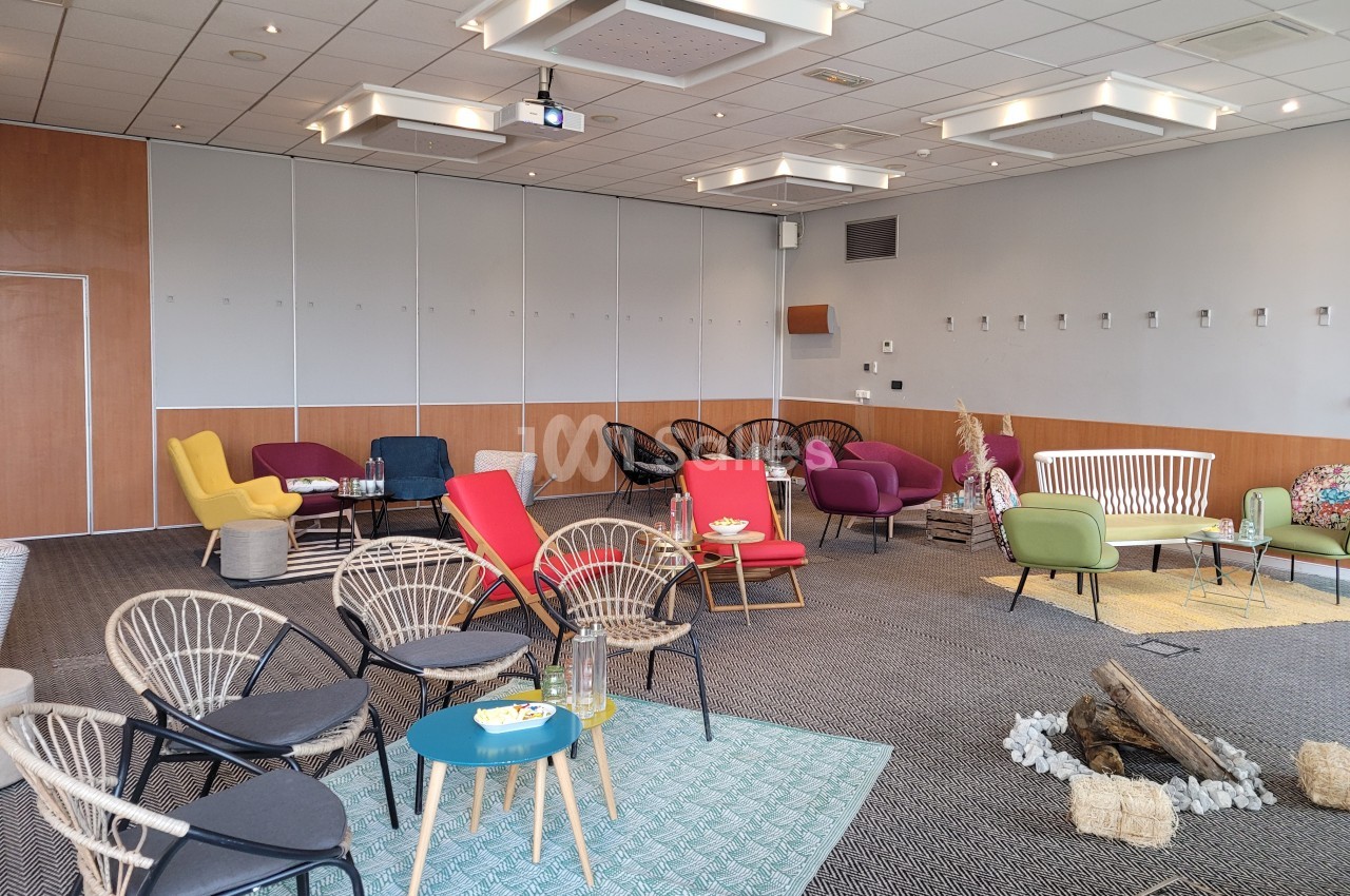 Salle de réunion aménagée avec des fauteuils colorés, des tapis et une décoration conviviale.