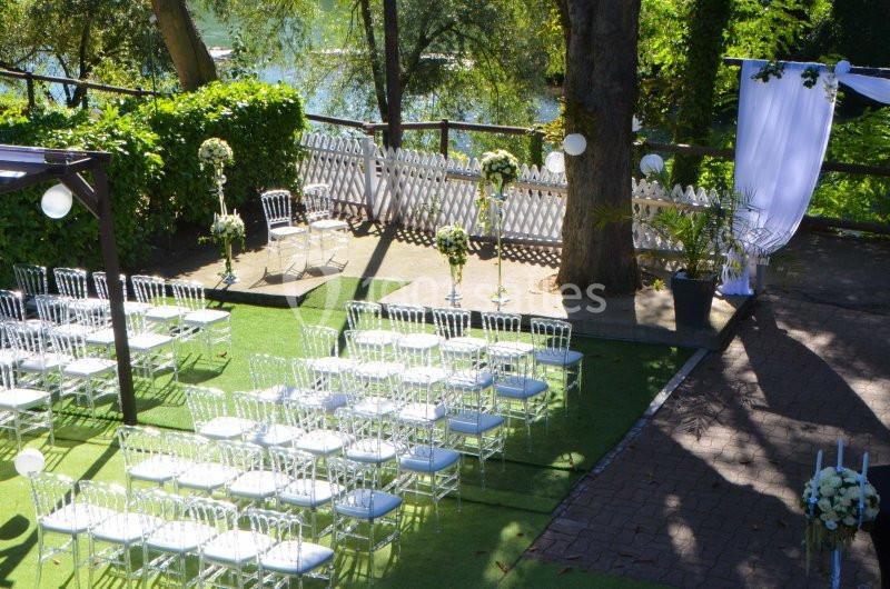 Chaises blanches alignées sur une pelouse, décorées pour une cérémonie en plein air avec arche et fleurs.