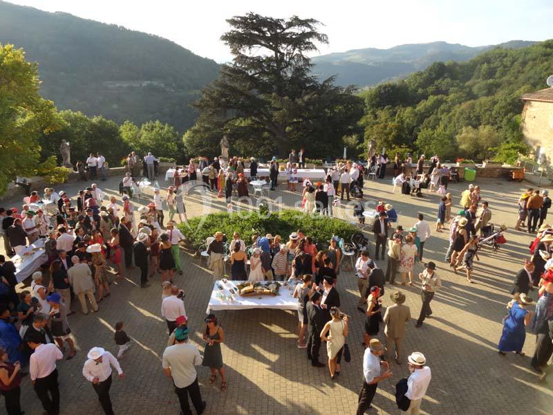 Groupe de personnes rassemblées en extérieur sur une terrasse avec vue sur des collines et des arbres.