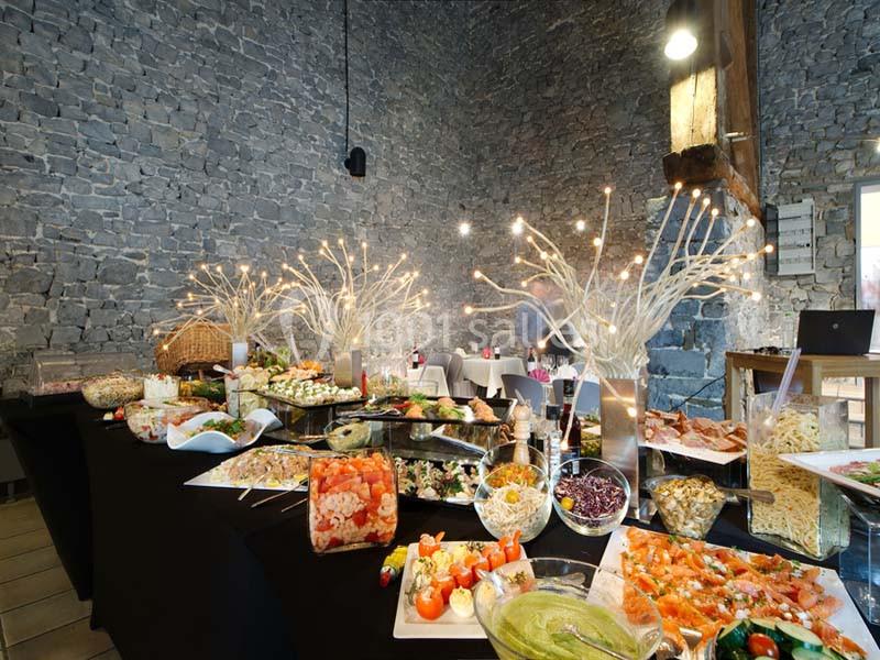 Buffet varié avec plats froids et chauds, disposé dans une salle en pierre avec décorations lumineuses.