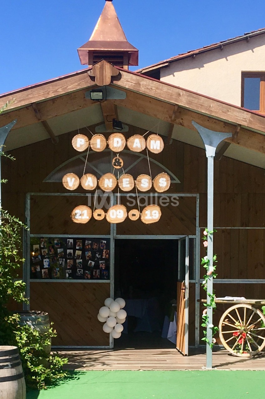 Entrée décorée d'une salle de réception avec des panneaux en bois affichant des prénoms et une date, ballons blancs en…