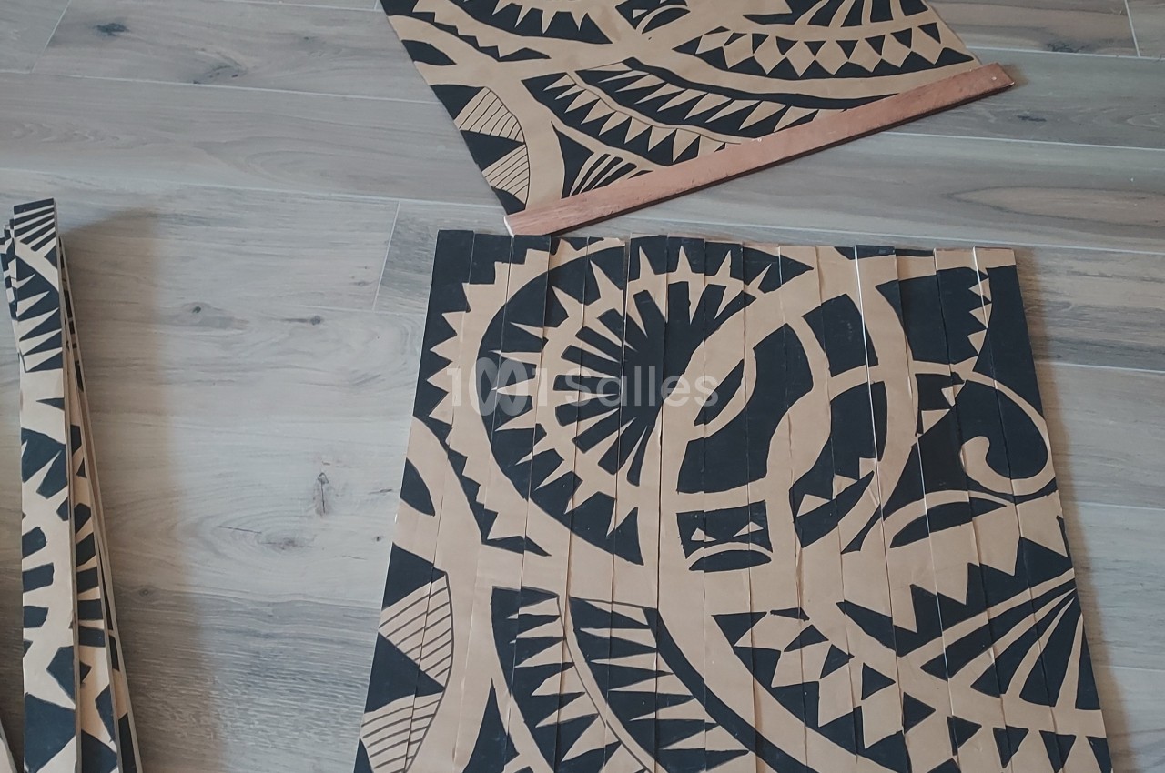 Panneaux en bois décorés de motifs noirs géométriques et tribaux, posés sur un sol en parquet clair.
