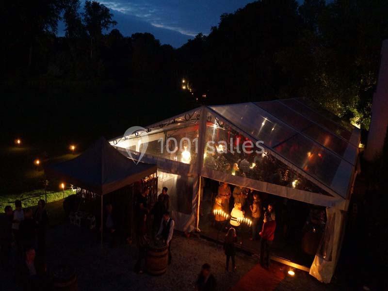 Tente transparente éclairée de nuit accueillant des invités lors d'un événement en extérieur.