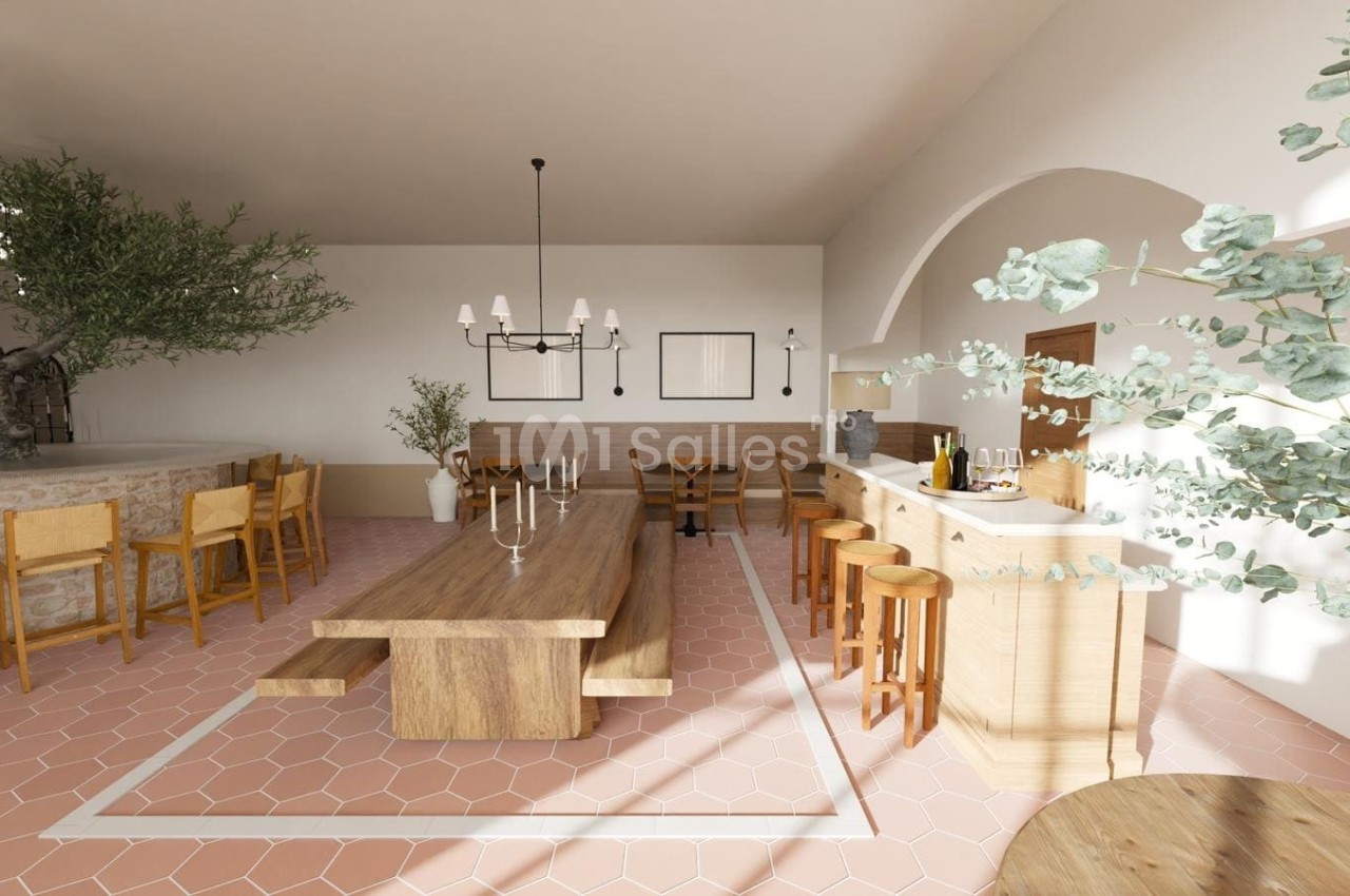 Salle lumineuse avec grande table en bois, chaises en bois clair, bar à droite et sol en carreaux rose pâle.