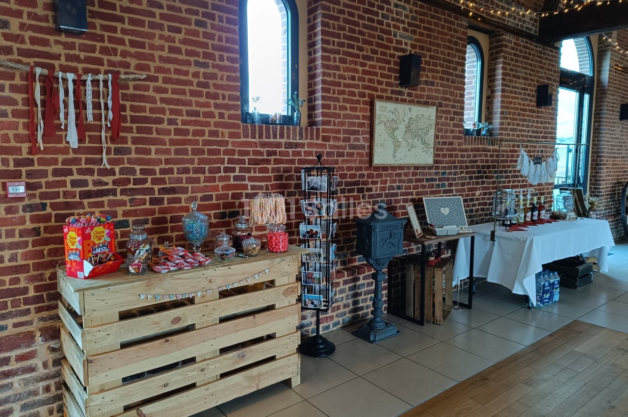Stand de confiseries et décorations dans une salle en briques rouges avec des tables et des présentoirs.