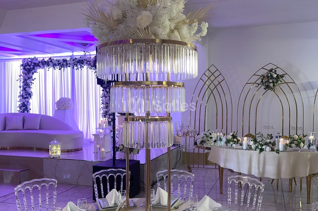 Centre de table élégant avec pampas et fleurs blanches, entouré de décorations lumineuses dans une salle de réception.