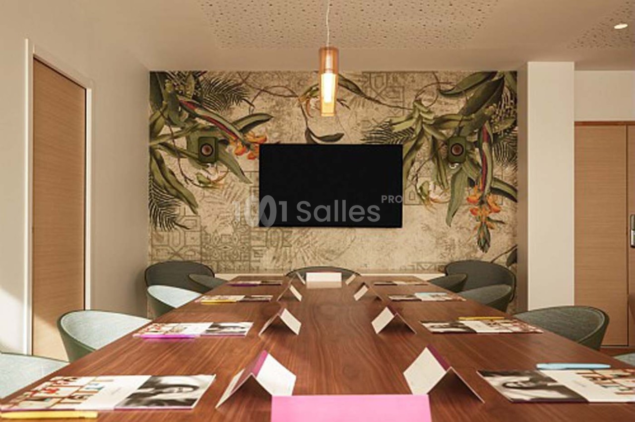 Salle de réunion avec une grande table en bois, des chaises modernes, un écran mural et une décoration tropicale.