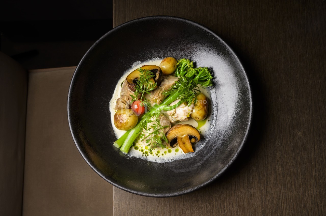 Assiette de légumes et champignons cuisinés, accompagnés de pommes de terre et d'une sauce crémeuse.