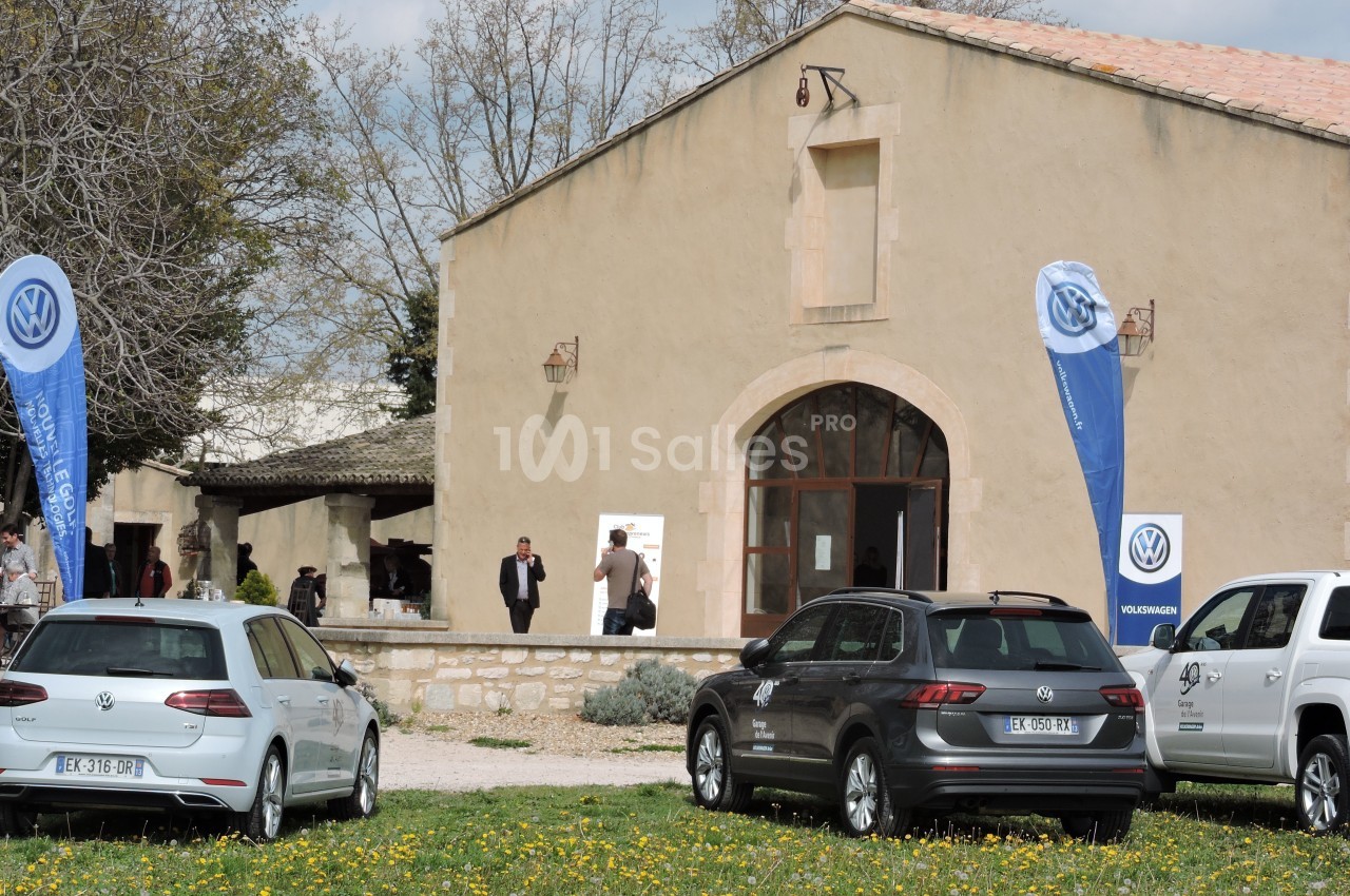 Trois voitures Volkswagen stationnées devant un bâtiment en pierre avec des drapeaux de la marque.