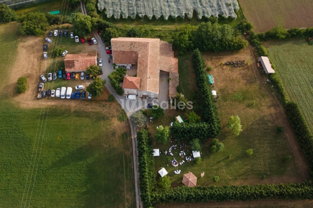Vue aérienne d'une grande propriété rurale avec bâtiments en pierre, espaces verts et voitures stationnées.