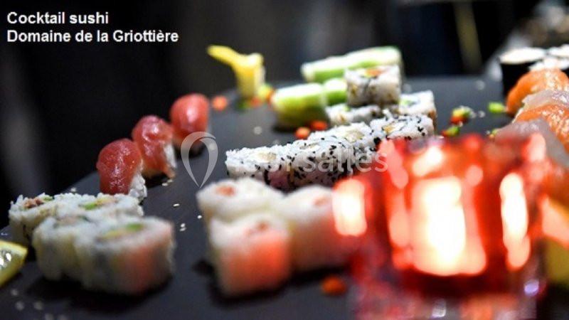 Plateau de sushis variés présentés sur une table sombre, avec une bougie rouge floue au premier plan.