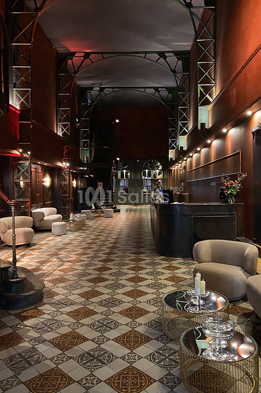 Hall d'entrée spacieux avec sol carrelé, mobilier moderne, comptoir d'accueil et éclairage tamisé.