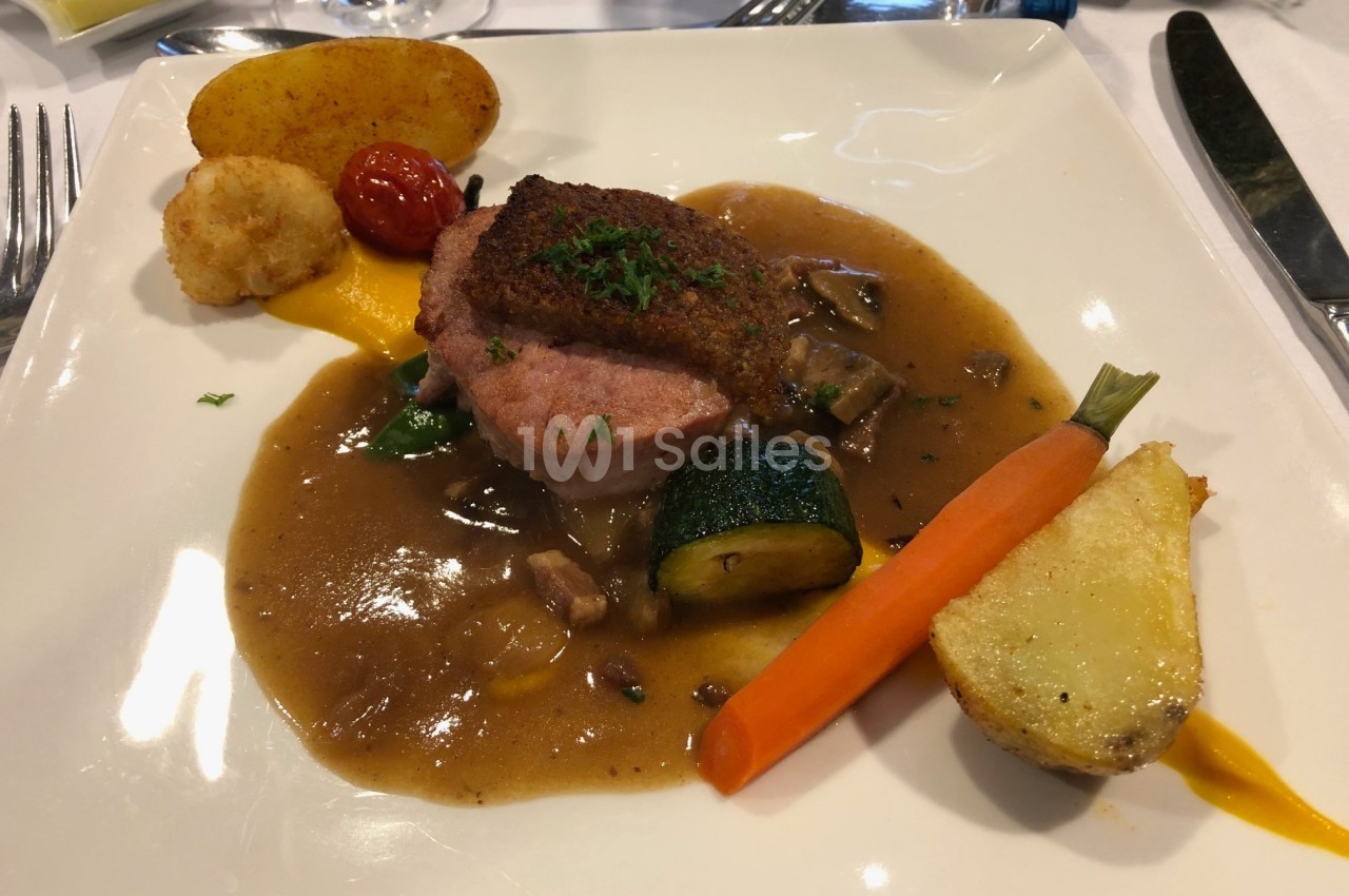 Assiette de viande garnie de légumes, sauce brune, carotte, courgette, pomme de terre et tomate cerise.