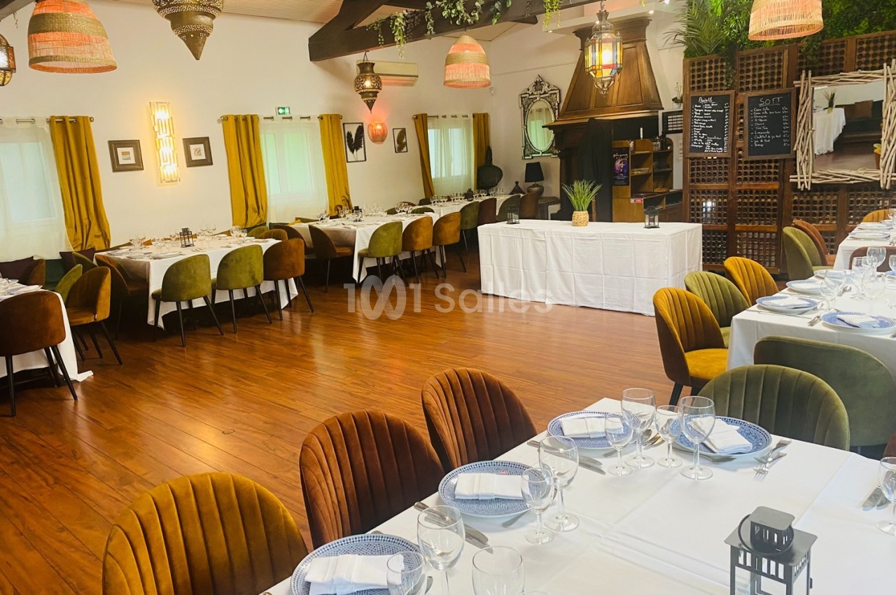 Salle de restaurant décorée avec des tables dressées, des chaises colorées et des luminaires suspendus.