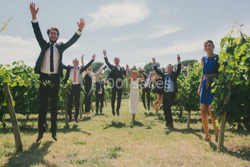 Des personnes en tenue élégante sautent joyeusement dans un vignoble par une journée ensoleillée.