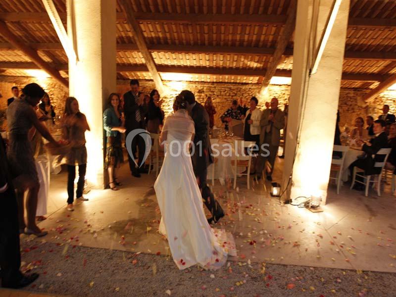 Un couple danse au centre d'une salle éclairée, entouré d'invités et de pétales de fleurs au sol.
