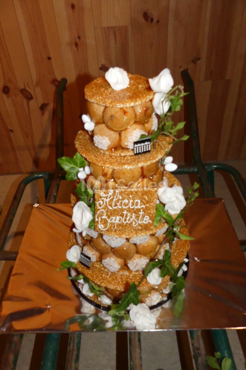 Pièce montée en choux décorée de feuilles, fleurs en sucre et inscription ’Alicia Baptiste’ sur une plaque.